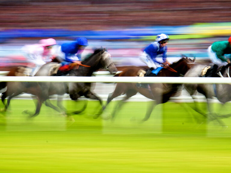 Horses and jockeys racing at speed on a grass track