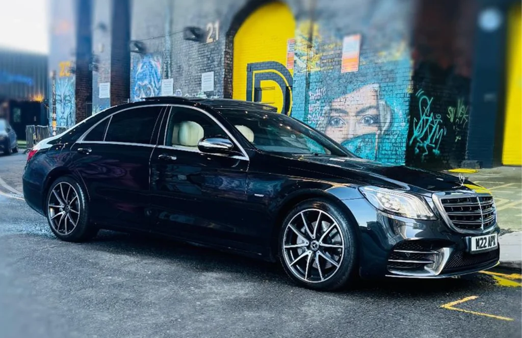 A black Mercedes-Benz S-Class from the Apex fleet parked on a city street at night