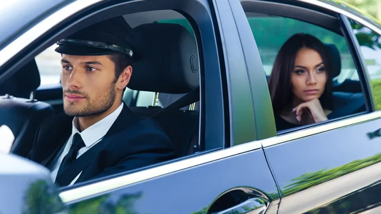 Professional chauffeur driving a luxury car with a thoughtful passenger in the back seat, showcasing a premium transportation experience.