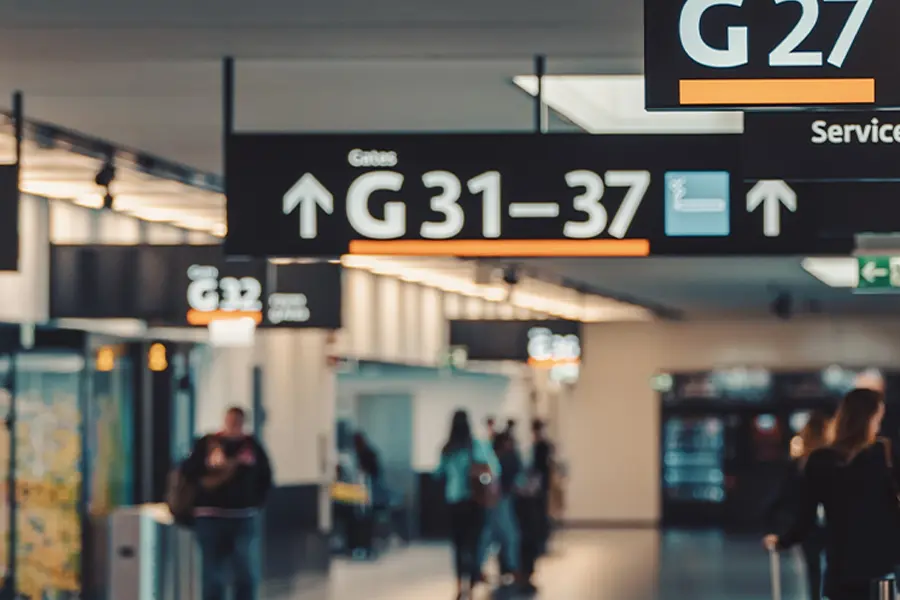 Airport terminal signage indicating gates G31 to G37, with travelers walking in the background. The image captures the modern design and busy atmosphere of an airport.