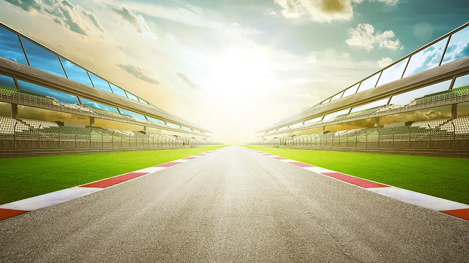 An empty racecourse at sunrise with grandstands either side of the track