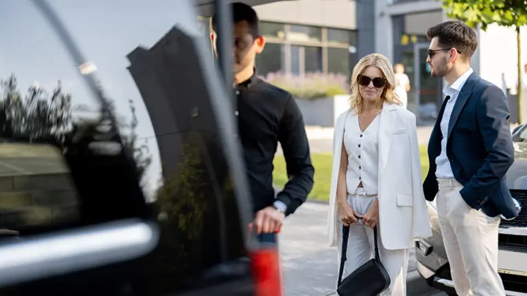 Professional women in stylish attire walking near a luxury vehicle, showcasing modern urban ambiance and contemporary fashion trends.