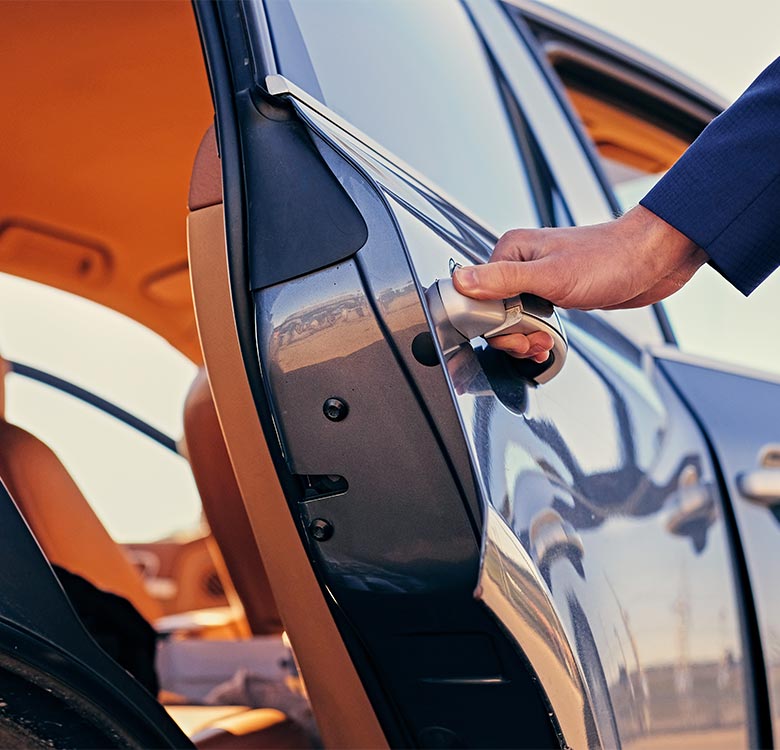 Birmingham's best luxury car service - hand reaching for the door handle of a modern car, showcasing a sleek vehicle design and elegant interior elements.