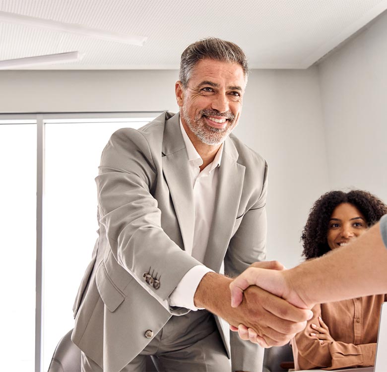 Business professionals engaging in a handshake during a meeting, showcasing collaboration and networking in a modern office environment.